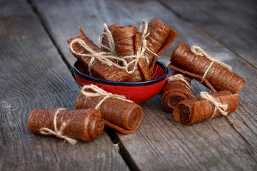 Handmade apple pastille tied with linen thread in a ceramic bowl on wooden background