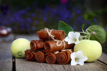 Handmade twisted apple pastille tied with linen thread on a wooden background with apples