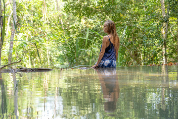 Young woman near turquoise water of cascade waterfall at tropical rain forest, island Koh Phangan, Thailand