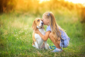 cute girl walks with her beagle puppy in the park at sunset, best friend