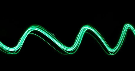 Long exposure, light painting photography.  Vibrant abstract streaks of neon green color against a black background.
