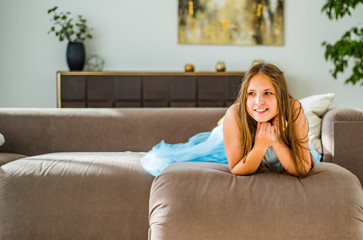 portrait of young teenager brunette girl with long hair lying on sofa at home