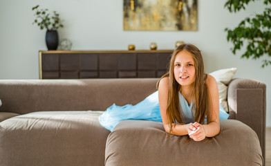 portrait of young teenager brunette girl with long hair lying on sofa at home