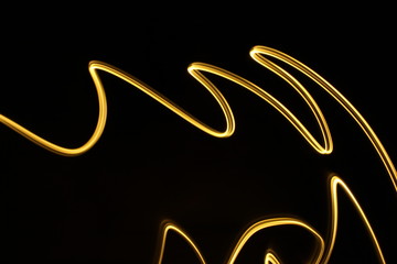 Long exposure, light painting photography.  Vibrant  abstract streaks of neon gold color against a black background.