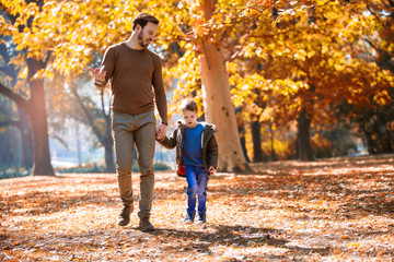 Happy father and little son playing and having fun outdoors over autumn park background