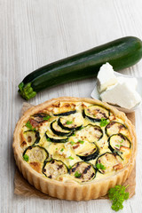 Homemade courgette and feta quiche on white wooden table