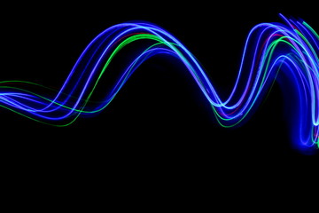 Long exposure, light painting photography.  Vibrant streaks of neon multi color against a black background.