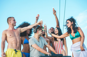 Happy friends drinking champagne in summer boat party - Young millennials people having fun...