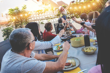 Happy family taking a selfie photo with smartphone camera at barbecue dinner in house backyard - Mature people having fun with new trend technology - Focus on close-up man's hand with wine glass