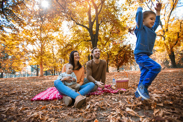 Fototapeta premium Happy family of four having fun together in the park in autumn