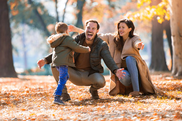 Young family having fun in the autumn park with his son.