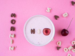 cereal breakfast bowl with yogurt and cherry on pink background top view