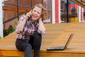 girl laughing talking on cell phone sitting on a wooden floor