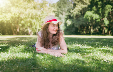 Woman outdoor portrait. Happy, young woman laying on green grass, in summer park.