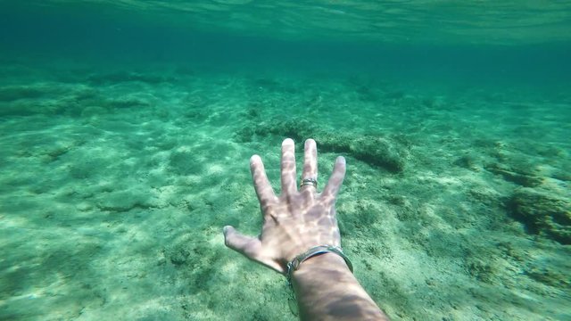 reaching human hand underwater, white skin, sunbeams, sun rays