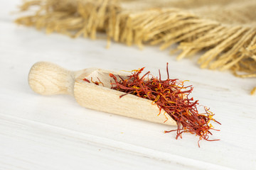 Lot of whole dry shaffron thread with wooden scoop and jute cloth on white wood