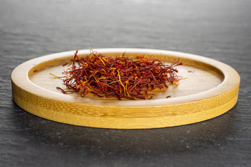 Lot of whole dry shaffron thread on bamboo plate on grey stone