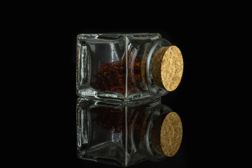 Lot of whole dry shaffron thread in glass bottle with cork cap isolated on black glass