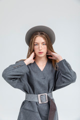 Portrait of young lady in grey autumn outfit posing hands on neck isolated on white background