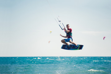 Professional kiter makes the difficult trick on a beautiful background. Kitesurfing Kiteboarding action photos man among waves quickly goes