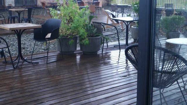 Wet chairs and tables in the empty cafe in the rain on a summer day, background