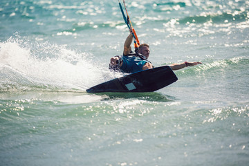 Obraz premium Professional kiter makes the difficult trick on a beautiful background. Kitesurfing Kiteboarding action photos man among waves quickly goes