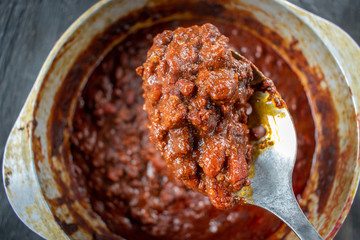 spoonful of rustic homemade chili with beans over pot flat lay