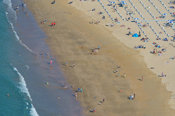 Aerial View From The Mountain Of People Relaxing On Beach In Spain.