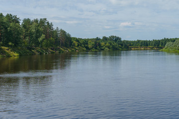 calm plain river among the banks covered with forest