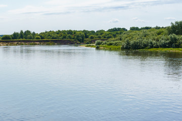 calm plain river among the banks covered with forest