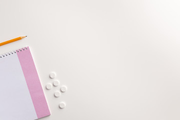 Notepad, pencil and pills on white background. Medical concept. Flat lay.
