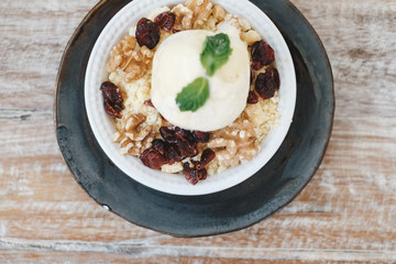 Apple crumble dessert with vanilla ice cream on the top on wooden table top view