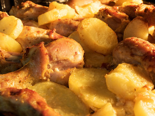 Appetizing chicken with baked potatoes in oven