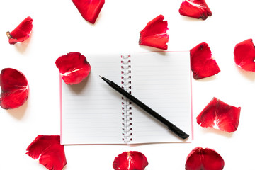 Rose petals, pen and note books on white background