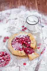 Homemade fruit pie (galette) made with fresh raspberries with powdered sugar on wooden table. Open pie, raspberry tart. Summer berry dessert.