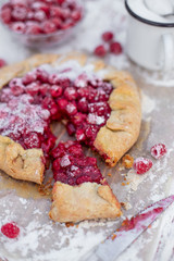 Homemade fruit pie (galette) made with fresh raspberries with powdered sugar on wooden table. Open pie, raspberry tart. Summer berry dessert.