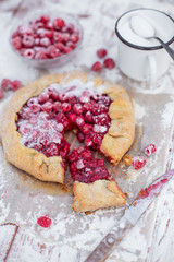Homemade fruit pie (galette) made with fresh raspberries with powdered sugar on wooden table. Open pie, raspberry tart. Summer berry dessert.