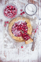 Homemade fruit pie (galette) made with fresh raspberries with powdered sugar on wooden table. Open pie, raspberry tart. Summer berry dessert. Flat lay
