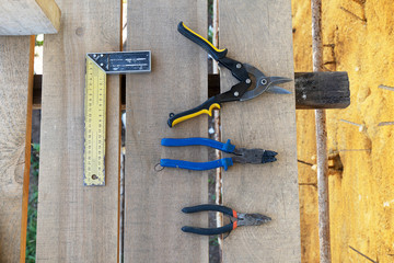 Construction tools ruler angular measuring, pliers, scissors for iron. On wooden scaffolding lies a...