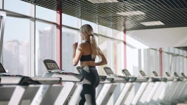Fitness woman running on treadmill in gym. Pretty girl having cardio training.