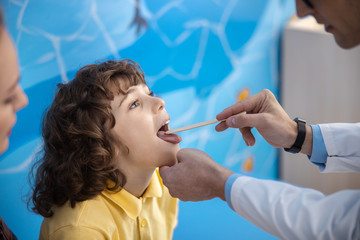 Doctor is examining kid throat in office stock photo