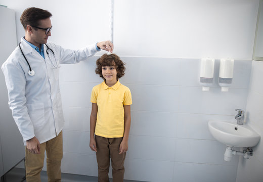 Smiling pediatrician is measuring boy size stock photo