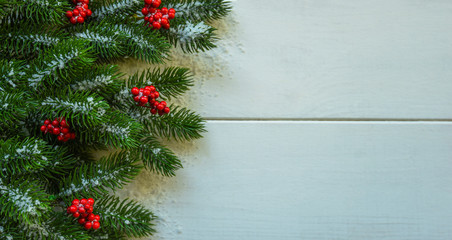 Christmas decoration with fir branches and red berries on a rustic wooden background. Christmas, winter, new year concept. Flat lay, top view, copy space.