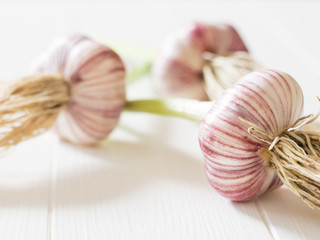 Three heads of fresh, large garlic on a white table. Component of traditional medicine.