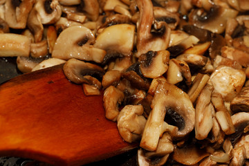 Fried champignon mushrooms in a pan closeup background texture