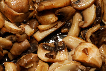 Fried champignon mushrooms in a pan closeup background texture