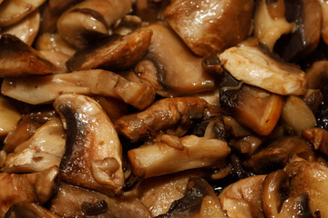 Fried champignon mushrooms in a pan closeup background texture