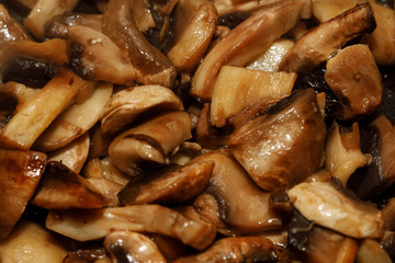 Fried champignon mushrooms in a pan closeup background texture