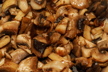 Fried champignon mushrooms in a pan closeup background texture