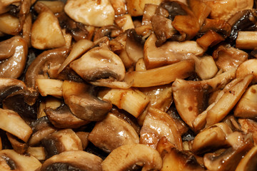 Fried champignon mushrooms in a pan closeup background texture